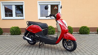 rotes Moped Sym Mio für Klasse AM vor dem Eingang der Fahrschule